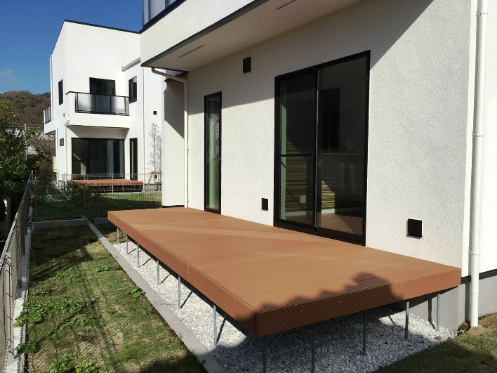 白い建物に芝庭、ウッドデッキ！屋外空間が充実しています。No6区画からNo4区画を見る