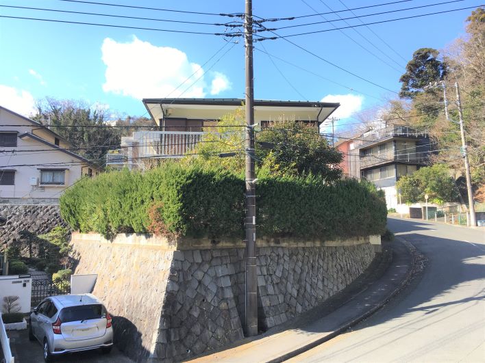 頑丈石垣と青々とした生垣の上に建つ建物。屋根のラインがクッキリとして潔さを感じます。